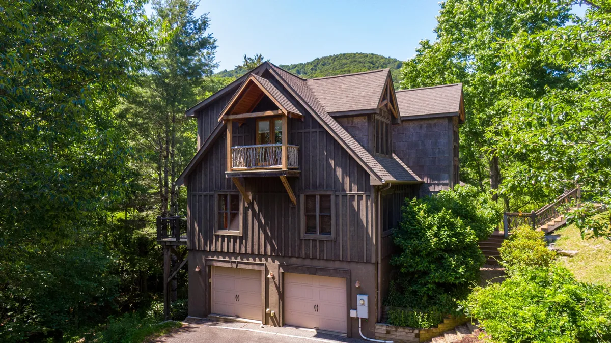This image showcases the charming wooden facade of Parkway Retreat, complete with a balcony and surrounded by lush greenery. The exterior invites guests to imagine the endless outdoor possibilities for kids and families, from running across the green yard to spotting wildlife or enjoying sunset views from the balcony.