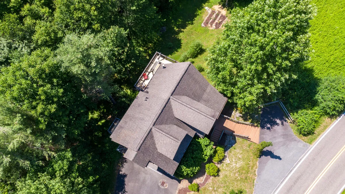 A peaceful garden area fills the frame, with the house roof peeking out amid mature trees and a welcoming driveway. The scene invites exploration and highlights the natural beauty surrounding Parkway Retreat, ideal for outdoor gatherings, play, and relaxed family time in nature.